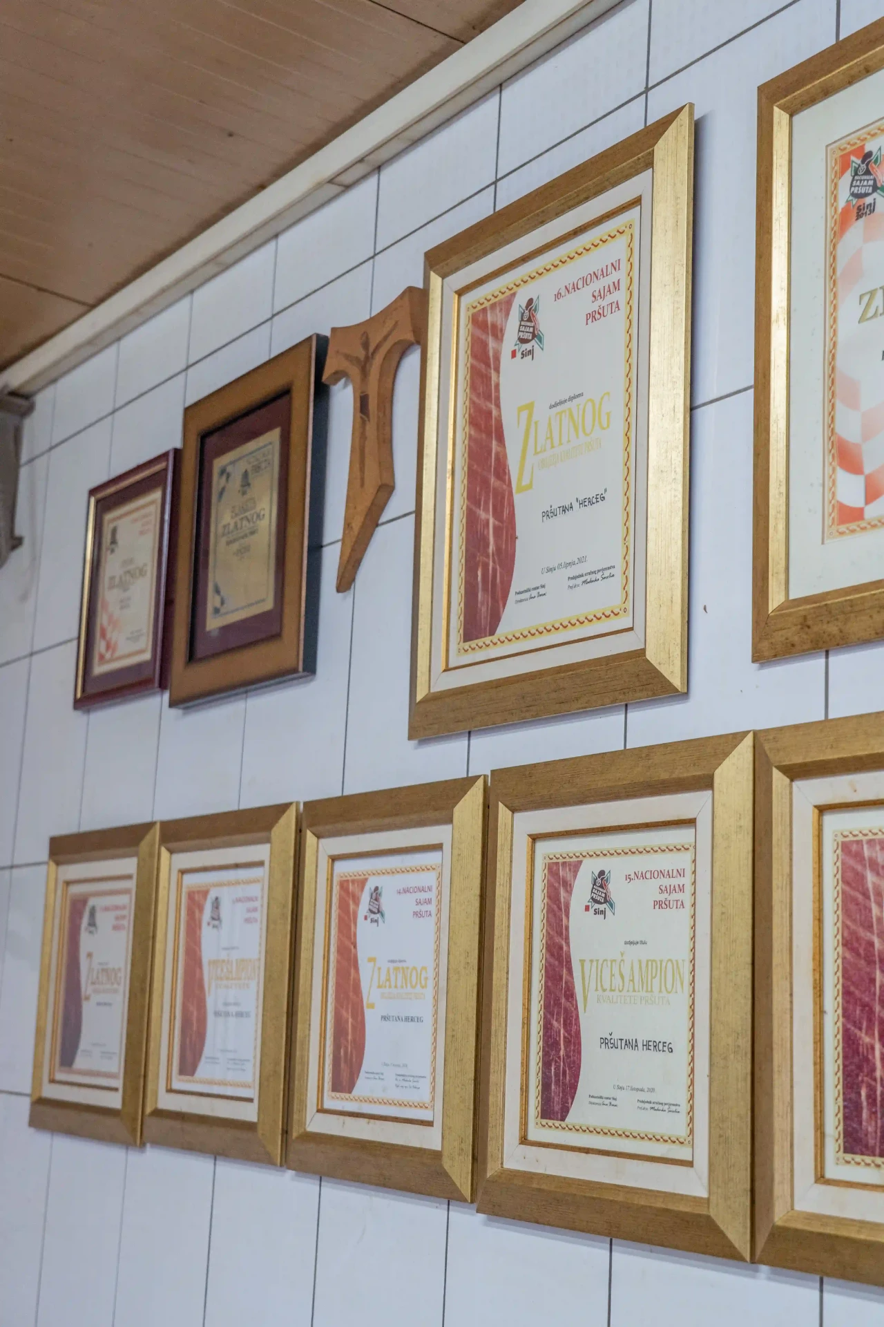 Uokvirene diplome s nacionalnih sajmova pršuta na zidu pršutane
